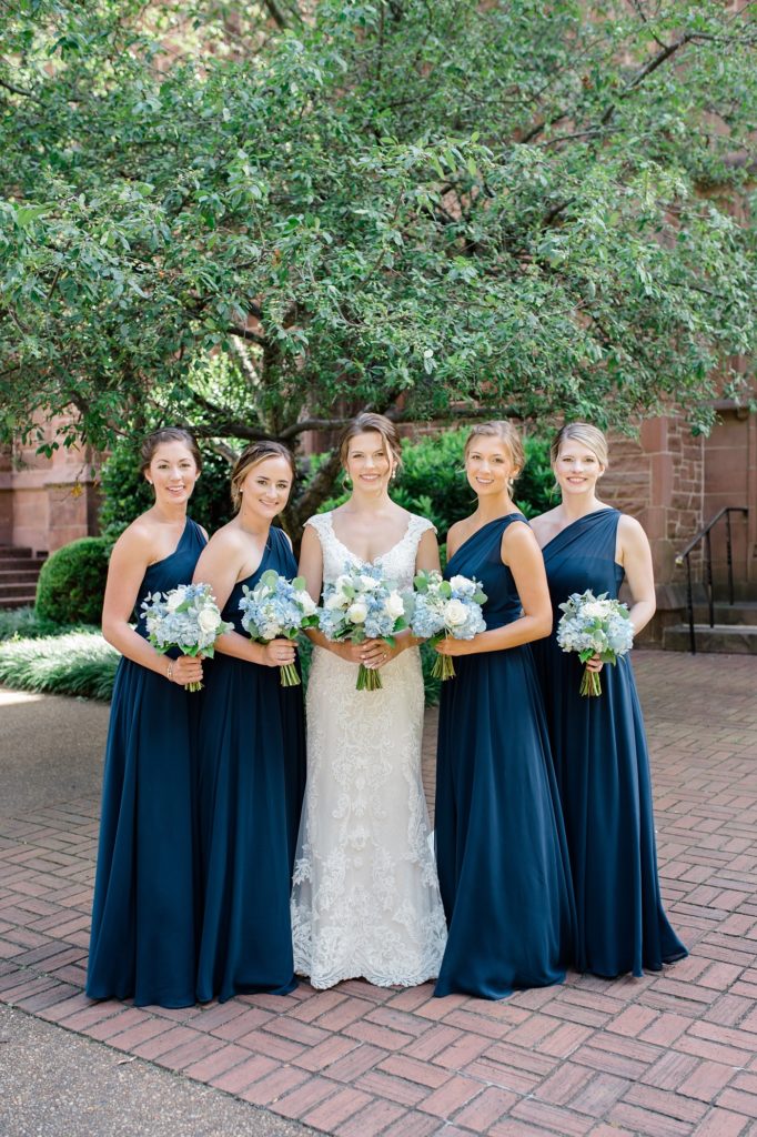 bride and bridesmaids smiling outside of a church