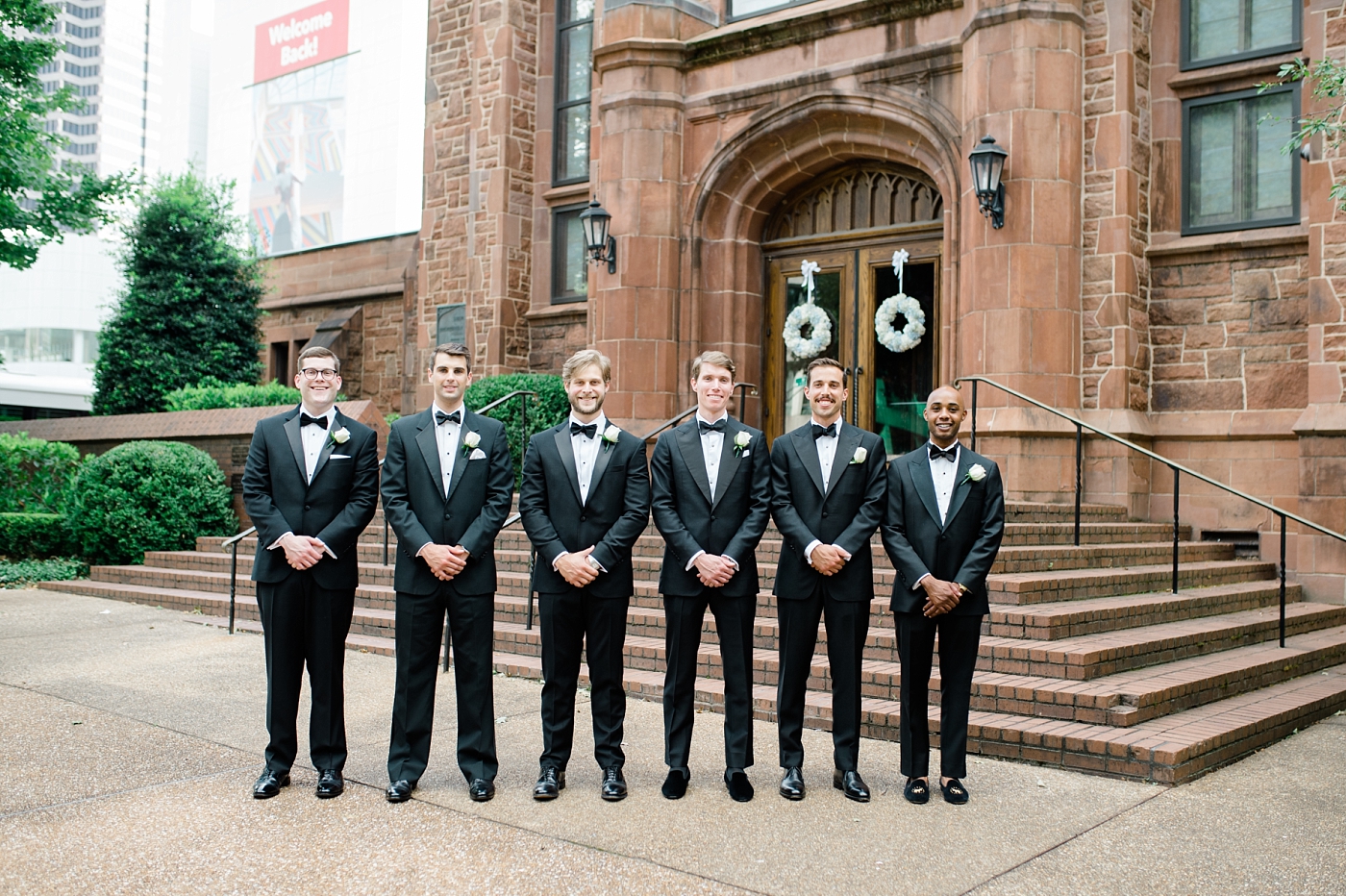 groom and groomsmen smiling outside of a church