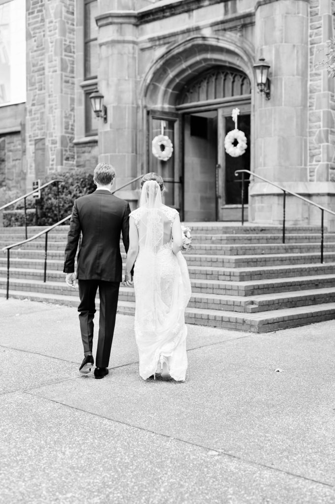 backs of bride and groom walking into a church