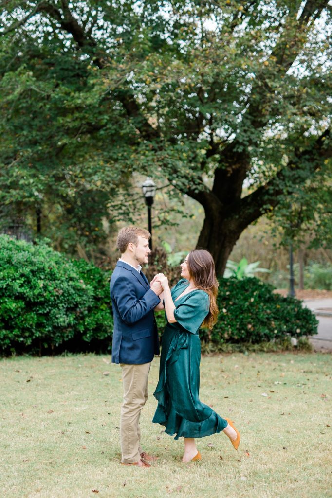 couple dancing for their couple smiling and holding their dog for piedmont park engagement photos