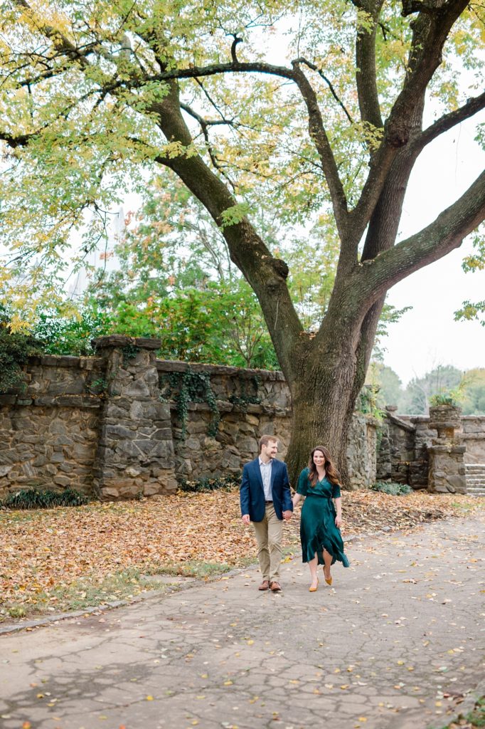 couple walking together for their couple smiling and holding their dog for piedmont park engagement photos