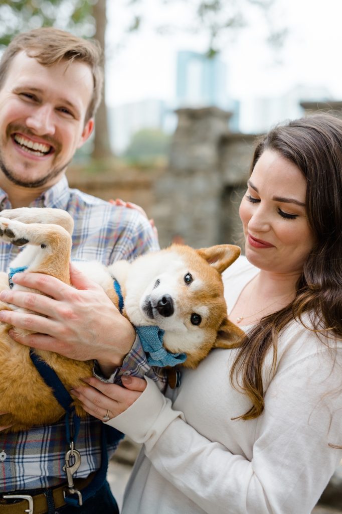 couple laughing with their dog for couple smiling and holding their dog for piedmont park engagement photos