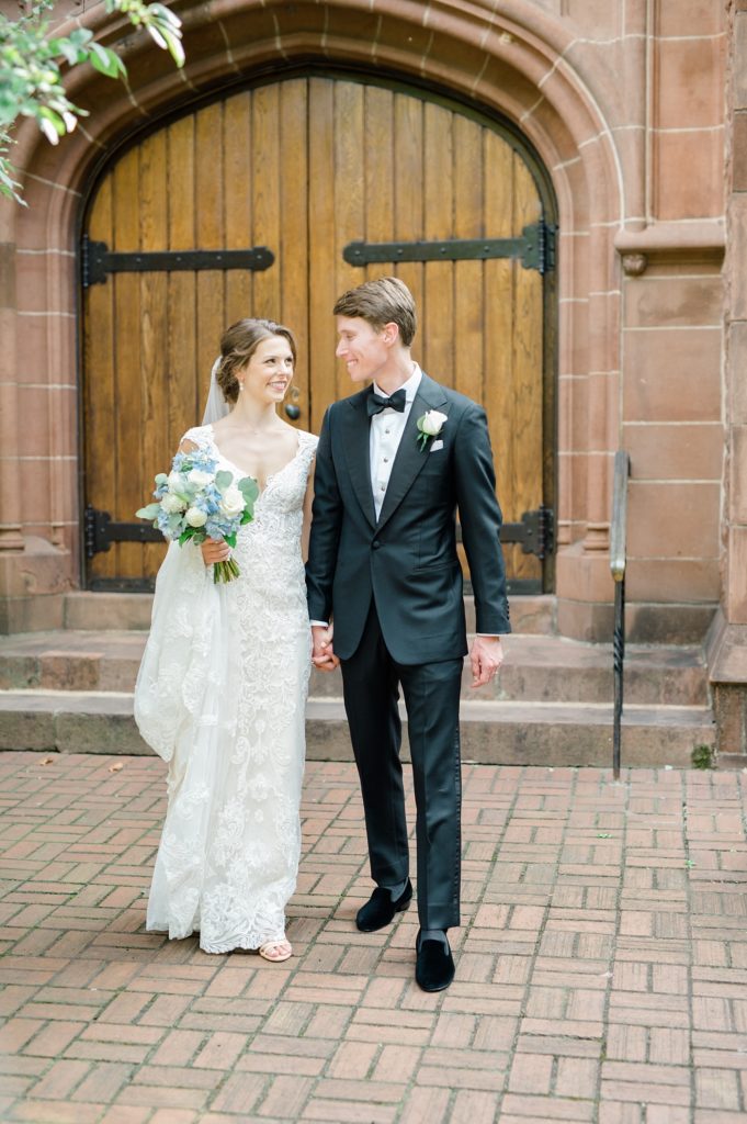bride and groom holding hands in front of a church
