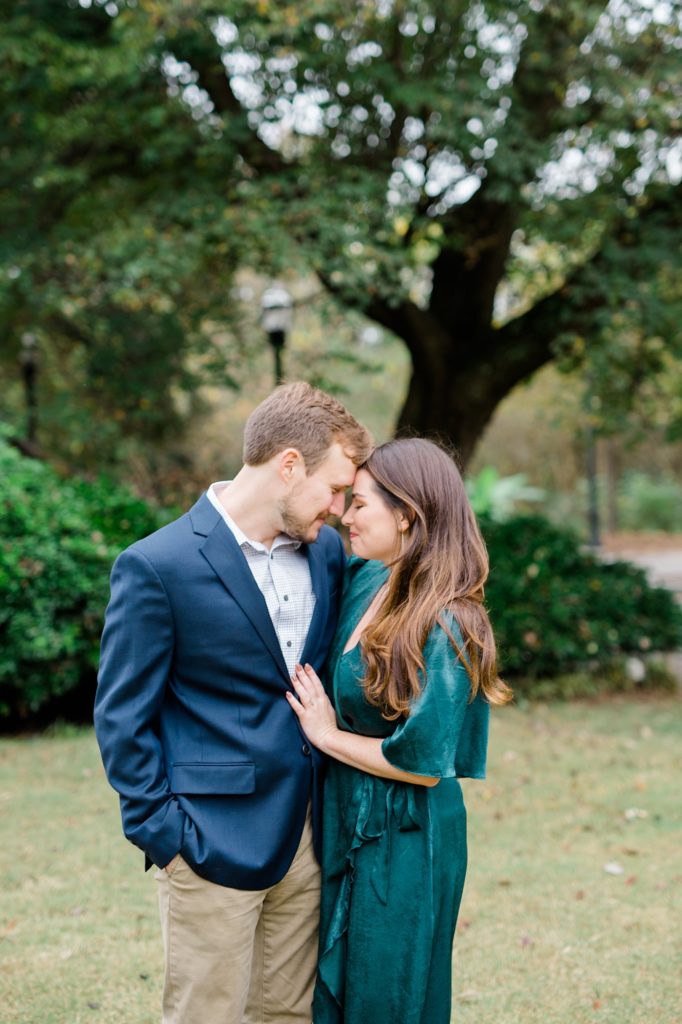 couple embracing for their couple smiling and holding their dog for piedmont park engagement photos